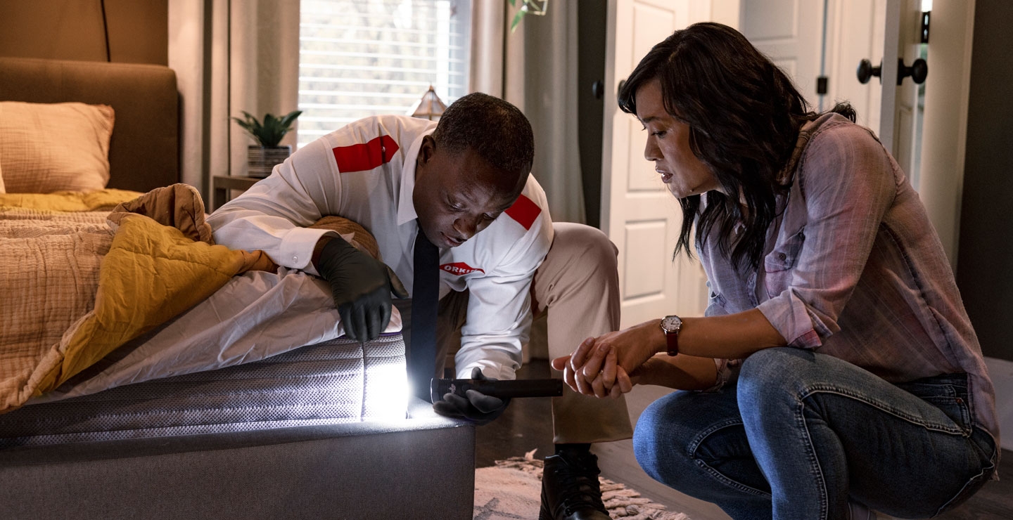 An Orkin Pro inspecting a customer's mattress for bed bugs with a flashlight